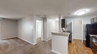Located at 317 Lynn Rd in Raleigh, NC, this single-floor residence offers a practical and well-organized layout designed for comfortable living. The kitchen serves as a central feature of the home, equipped with dark cabinetry, black appliances including a refrigerator and range, and a peninsula with granite-style countertops that doubles as a breakfast bar. Wood-look flooring runs through the kitchen and bathrooms, while plush carpeting covers the living areas and bedrooms, creating a warm, cohesive feel throughout.

The open living and dining area flows naturally from the kitchen, benefiting from ceiling light fixtures and a neutral color palette that keeps the space bright and versatile. Bedrooms are comfortably sized, each featuring ceiling fans and access to closets outfitted with wire shelving systems for organized storage.

Two full bathrooms mirror each other in design, each finished with wood-look flooring, gray vanity cabinetry, granite-style countertops, a single sink, and a tiled shower-tub combination. A dedicated laundry area accommodates a full-size washer and includes overhead wire shelving for additional storage. The residence combines functional design with clean, modern finishes throughout its single level.