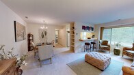 This thoughtfully designed one-bedroom, one-bathroom residence offers a functional and comfortable single-floor layout. The combined living, dining, and kitchen area forms the heart of the home, creating an open and connected atmosphere. The living room receives generous natural light through a large window, complemented by soft carpeting and neutral wall tones that lend a warm, inviting ambiance throughout.

The kitchen is a standout feature, showcasing a distinctive decorative tile floor runner, white cabinetry extending to the ceiling for ample storage, and a full suite of appliances. A pass-through breakfast bar with bar seating connects the kitchen directly to the living area, making it ideal for casual dining and entertaining. The adjacent dining area is illuminated by an elegant chandelier and provides a defined space for formal meals.

The primary bedroom is a well-proportioned retreat with soft carpet flooring, a large window offering outdoor views, and access to a dedicated walk-in closet. The full bathroom features a tiled tub-shower combination and clean, classic finishes. An additional closet provides further storage convenience. The overall palette of warm neutrals and soft tones creates a cohesive and comfortable living environment throughout the entire space.
