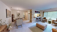 This thoughtfully designed one-bedroom, one-bathroom residence offers a functional and comfortable single-floor layout. The combined living, dining, and kitchen area forms the heart of the home, creating an open and connected atmosphere. The living room receives generous natural light through a large window, complemented by soft carpeting and neutral wall tones that lend a warm, inviting ambiance throughout.

The kitchen is a standout feature, showcasing a distinctive decorative tile floor runner, white cabinetry extending to the ceiling for ample storage, and a full suite of appliances. A pass-through breakfast bar with bar seating connects the kitchen directly to the living area, making it ideal for casual dining and entertaining. The adjacent dining area is illuminated by an elegant chandelier and provides a defined space for formal meals.

The primary bedroom is a well-proportioned retreat with soft carpet flooring, a large window offering outdoor views, and access to a dedicated walk-in closet. The full bathroom features a tiled tub-shower combination and clean, classic finishes. An additional closet provides further storage convenience. The overall palette of warm neutrals and soft tones creates a cohesive and comfortable living environment throughout the entire space.