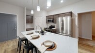 This contemporary apartment offers 870 square feet of thoughtfully designed living space. The open-concept layout creates a seamless flow between the living areas, enhancing the sense of spaciousness. The gourmet kitchen is a standout feature, boasting sleek cabinetry, stainless steel appliances, and a generous island with seating, perfect for casual dining or entertaining.

The two bedrooms are well-proportioned, with the primary bedroom measuring 160 square feet. Both bedrooms feature plush carpeting and ample closet space with wire shelving systems. The two full bathrooms are finished with modern fixtures, including vanities with ample storage and walk-in showers.

Throughout the apartment, you'll find a cohesive design aesthetic with neutral tones and clean lines. The living areas and kitchen boast beautiful hardwood flooring, while the bedrooms offer cozy carpeting. Large windows allow for plenty of natural light, and the unit is equipped with efficient split-system air conditioning for year-round comfort.

Additional amenities include in-unit laundry facilities and extra storage space. The apartment's thoughtful design and high-quality finishes create a comfortable and stylish living environment in the heart of Fitchburg, Wisconsin.