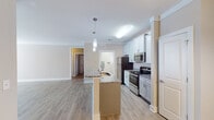 Located at 4020 St Croix Ln in Mebane, NC, this single-floor residence offers a thoughtfully designed layout with modern finishes and a cohesive, neutral color palette throughout. The open-concept kitchen serves as the heart of the home, showcasing crisp white shaker-style cabinetry, granite countertops, and a full suite of stainless steel appliances including a refrigerator, electric range, and built-in microwave. A central island with a sink and pendant lighting above adds both functionality and style, flowing seamlessly into the living area. Light wood-tone luxury vinyl plank flooring extends through the main living spaces, complemented by clean white trim and crown molding details. The bedroom features plush carpet, a ceiling fan, a window with natural light, and access to a spacious closet with built-in wire shelving. The bathroom is finished with tile flooring, a granite-topped vanity with undermount sink, and a full tub-shower combination. A dedicated laundry area with wire shelving and washer/dryer hookups adds convenience. The entry foyer features an elegant arched white door and hardwood-style flooring, creating a welcoming first impression. This residence combines practical living with clean, contemporary design.