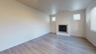 Located in Gig Harbor, WA, this well-appointed two-story home offers a thoughtfully designed layout with modern finishes across both levels. The main floor features wood-look flooring throughout, beginning with a welcoming entryway that leads past a convenient half bath with a pedestal sink toward the heart of the home. The open-concept kitchen is a standout, showcasing white shaker cabinetry, quartz countertops, a central island with pendant lighting, stainless steel appliances, and a dedicated dining area. Adjacent to the kitchen, the living room is bright and airy, with recessed lighting, a wall-mounted mini-split system, a clean-lined fireplace, and multiple windows that bring in natural light. Upstairs, carpeted bedrooms offer a comfortable retreat, including a spacious primary bedroom with a ceiling fan, ample natural light, and access to a generously sized walk-in closet with built-in wire shelving. The full bathroom on the upper level features a glass-enclosed shower, light wood vanity cabinetry, quartz counters, and elegant hexagonal tile flooring. Throughout the home, a neutral color palette, clean architectural lines, and quality materials combine to create a fresh, move-in-ready living environment.