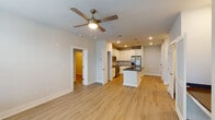 This single-story residence in Destin, Florida offers a thoughtfully designed open-concept floor plan with two bedrooms and two full bathrooms. Light-toned wood-look flooring runs throughout the home, creating a cohesive and airy feel across all living areas.

The kitchen serves as the centerpiece of the main living space, anchored by a central island with a dark countertop, an integrated sink, and elegant brass pendant lighting overhead. White shaker-style cabinetry lines the walls, complemented by a classic subway tile backsplash and a full suite of stainless steel appliances, including a range, microwave, and refrigerator. The kitchen opens seamlessly into the living area, which features a ceiling fan and a glazed door providing natural light and outdoor access.

The bedrooms are well-proportioned, each with ceiling fans and windows that bring in natural light. One bedroom includes a walk-in closet with built-in shelving. The two bathrooms mirror the home's clean aesthetic, both featuring white subway tile, dark countertops, and white cabinetry. One bathroom offers a soaking tub with a tiled surround, while the other features a walk-in shower with a sliding glass door and brushed nickel hardware throughout.