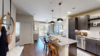 Located at 3600 N A W Grimes Blvd in Round Rock, TX, this 1-bedroom, 1-bathroom residence offers a thoughtfully designed open-concept layout that maximizes its efficient footprint. The kitchen is a standout feature, showcasing dark espresso cabinetry, a white subway tile backsplash, stainless steel appliances, and a large granite-topped island with pendant lighting — ideal for casual dining or entertaining. Wood-style flooring flows through the main living areas, lending warmth and continuity throughout the space. The living room is bright and inviting, benefiting from natural light and sliding glass doors that open to a private balcony with outdoor views of the surrounding community. The bedroom offers a comfortable retreat with plush carpet, a ceiling fan, and large windows dressed with stylish drapes, along with direct access to the bathroom and a dedicated closet. The bathroom continues the refined aesthetic with granite countertops, dark wood cabinetry, a large vanity mirror, and a tiled tub/shower combination. Recessed lighting and modern pendant fixtures throughout the home contribute to a clean, contemporary ambiance well-suited for everyday living in Round Rock, Texas.