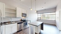 Located at 161 Concord Exchange in South Saint Paul, MN, this one-bedroom, one-bathroom unit offers a well-designed layout across a single floor. The open-concept kitchen serves as the heart of the space, featuring white shaker-style cabinetry, a mosaic tile backsplash, stainless steel appliances including a refrigerator, range, and microwave, and a striking central island clad in a marble-look finish with pendant lighting above. Durable hardwood-style flooring runs throughout the main living and kitchen areas, adding warmth and a modern aesthetic. The living area is bright and open, with large windows that frame outdoor views and allow natural light to fill the room. The bedroom is generously sized, finished with plush carpeting and a wide window that continues the theme of natural light and outdoor views. A dedicated walk-in closet with wire shelving provides ample storage. The full bathroom is clean and functional, equipped with a tub/shower combination, white vanity, and hardwood-style flooring that ties the space together cohesively. Neutral gray tones throughout create a calm, contemporary ambiance well-suited for everyday living.