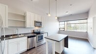 Located at 161 Concord Exchange in South Saint Paul, MN, this one-bedroom, one-bathroom unit offers a well-designed layout across a single floor. The open-concept kitchen serves as the heart of the space, featuring white shaker-style cabinetry, a mosaic tile backsplash, stainless steel appliances including a refrigerator, range, and microwave, and a striking central island clad in a marble-look finish with pendant lighting above. Durable hardwood-style flooring runs throughout the main living and kitchen areas, adding warmth and a modern aesthetic. The living area is bright and open, with large windows that frame outdoor views and allow natural light to fill the room. The bedroom is generously sized, finished with plush carpeting and a wide window that continues the theme of natural light and outdoor views. A dedicated walk-in closet with wire shelving provides ample storage. The full bathroom is clean and functional, equipped with a tub/shower combination, white vanity, and hardwood-style flooring that ties the space together cohesively. Neutral gray tones throughout create a calm, contemporary ambiance well-suited for everyday living.