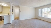 Located at 16031 Pioneer Blvd in Norwalk, California, this single-floor unit offers a clean, functional layout with a bright and neutral interior throughout. The open living area is finished with plush carpeting, crown molding, and a textured ceiling, creating a comfortable and well-maintained space. A window unit provides climate control, and a window overlooking greenery allows natural light to fill the room. The living area flows seamlessly toward a dedicated hallway leading to the private rooms.

The kitchen is efficiently designed with gray shaker-style cabinetry extending to the ceiling for ample storage, white countertops, and light wood-look flooring. Stainless steel appliances — including a full-size refrigerator, gas range, and dishwasher — complete the modern setup. A half-wall peninsula separates the kitchen from the living space, adding both definition and an open feel.

The bedrooms are carpeted and bright, each featuring windows with vertical blinds that allow for natural light and privacy. The bathroom includes a full tub and shower surround in crisp white, maintaining the unit's clean, move-in-ready aesthetic. Overall, the space presents a well-updated, practical living environment in a convenient Norwalk location.