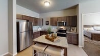 Located at 218 19th St SE in Watertown, South Dakota, this single-floor residence offers a well-designed, functional layout with a cohesive neutral color palette throughout. The open-concept kitchen is a standout feature, appointed with rich dark cabinetry, granite-style countertops, stainless steel appliances including a refrigerator, range, and microwave, and a central island with bar seating — ideal for both cooking and casual dining. The kitchen flows seamlessly into the living area, which is carpeted and bathed in natural light from large sliding glass doors fitted with vertical blinds. The bedrooms are comfortably sized with plush carpeting, natural window light, and baseboard heating. The primary bedroom connects to a bathroom and a dedicated walk-in closet, providing ample storage. A second bathroom features granite countertops, dark wood cabinetry, and a shower-tub combination. Light wood-style flooring runs through the kitchen and bathroom areas, offering a clean contrast to the carpeted rooms. A dedicated laundry area accommodates a full-sized washer and dryer. The textured ceilings and warm, neutral tones create a consistent, inviting ambiance throughout the entire space.