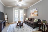 This single-story residence offers a thoughtfully designed layout across several distinct living areas. The kitchen serves as a functional centerpiece, featuring warm honey-toned cabinetry, dark granite countertops, stainless steel appliances including an over-the-range microwave and electric range, and light vinyl flooring. A breakfast bar with a built-in sink provides a natural transition into the adjoining living spaces.

The living room is bright and welcoming, with carpet flooring, crown molding, and a pair of French doors fitted with blinds that allow natural light while offering outdoor access. Gray-toned walls carry throughout the main living areas, lending a cohesive, contemporary feel.

The primary bedroom includes an arched alcove with built-in shelving and a dedicated desk area, carpeted floors, crown molding, and a window with outdoor views. A secondary bedroom also features carpet and a large window with natural light. Both bedrooms offer generous storage.

Two bathrooms are finished with dark granite vanity counters, medium-toned wood cabinetry, and wood-style flooring. One bathroom features a tub-shower combination with additional overhead cabinetry. Crown molding is a recurring detail throughout the home, adding a polished, consistent architectural character.