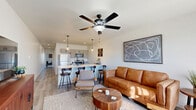 Located at 42 Manor Dr in Greenfield, Indiana, this well-appointed one-bedroom, one-bathroom unit offers a thoughtfully designed single-level layout that maximizes every square foot. The open-concept living and kitchen area forms the heart of the home, where light wood-tone flooring, recessed lighting, and a ceiling fan create a bright and airy atmosphere. The kitchen is equipped with stainless steel appliances — including a refrigerator, range, and microwave — complemented by gray shaker-style cabinetry and a striking quartz countertop island with a black matte faucet. The island doubles as a breakfast bar with seating, seamlessly connecting the kitchen to the living space. The living area is generous in scale, offering ample room for a full seating arrangement beneath pendant and ceiling lighting. The bedroom is comfortably sized, featuring its own ceiling fan and access to well-organized closet space, including a walk-in closet with wire shelving. The bathroom is finished with a marble-style quartz vanity, undermount sink, black hardware accents, and wood-look flooring, maintaining a cohesive modern aesthetic throughout. A dedicated laundry area adds everyday convenience. The overall design is clean and contemporary, with neutral tones that lend a calm, livable feel to the entire space.