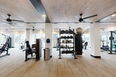 Located at 2291 Mercantile St in Castle Rock, Colorado, this well-equipped fitness center offers a generously sized, single-level layout designed to support a wide range of workout styles and fitness goals. The main workout area features light wood-plank flooring that transitions to low-pile commercial carpet in secondary zones, lending the space a clean, contemporary aesthetic throughout.

The facility is outfitted with an impressive array of equipment, including True-brand strength machines, treadmills, ellipticals, stationary bikes, and a dedicated functional training station stocked with kettlebells, medicine balls, battle ropes, and resistance accessories. Structural columns are integrated seamlessly into the open floor plan, and large windows along the perimeter admit abundant natural light while providing views of the surrounding Castle Rock community.

The ceiling design is a standout architectural feature, combining whitewashed wood planks with dark exposed beams and recessed lighting. Multiple ceiling fans are distributed throughout, ensuring effective air circulation across the full expanse of the floor.

A secondary room provides additional space for supplemental equipment and includes a water fountain. The restroom is finished to a high standard, featuring large-format marble-look tile flooring, ADA-compliant fixtures, matte black grab bars, and a sleek dual-sink vanity with backlit mirrors — delivering both functionality and style.