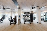 Located at 2291 Mercantile St in Castle Rock, Colorado, this well-equipped fitness center offers a generously sized, single-level layout designed to support a wide range of workout styles and fitness goals. The main workout area features light wood-plank flooring that transitions to low-pile commercial carpet in secondary zones, lending the space a clean, contemporary aesthetic throughout.

The facility is outfitted with an impressive array of equipment, including True-brand strength machines, treadmills, ellipticals, stationary bikes, and a dedicated functional training station stocked with kettlebells, medicine balls, battle ropes, and resistance accessories. Structural columns are integrated seamlessly into the open floor plan, and large windows along the perimeter admit abundant natural light while providing views of the surrounding Castle Rock community.

The ceiling design is a standout architectural feature, combining whitewashed wood planks with dark exposed beams and recessed lighting. Multiple ceiling fans are distributed throughout, ensuring effective air circulation across the full expanse of the floor.

A secondary room provides additional space for supplemental equipment and includes a water fountain. The restroom is finished to a high standard, featuring large-format marble-look tile flooring, ADA-compliant fixtures, matte black grab bars, and a sleek dual-sink vanity with backlit mirrors — delivering both functionality and style.