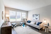 This single-floor residence offers a well-organized layout that balances comfort and functionality across its living spaces. The living room serves as the heart of the home, featuring wide windows that invite abundant natural light and views of the surrounding greenery. Dark wood-style flooring grounds the space, complementing the neutral wall tones throughout.

The kitchen is thoughtfully designed with white cabinetry, granite-style countertops, a mosaic tile backsplash, and stainless steel appliances including a gas range and full-size refrigerator. It opens directly into a dedicated dining area, which is anchored by a pendant light fixture and wood-style flooring, creating a cohesive and functional flow between the two spaces.

The residence includes two bedrooms, both finished with plush carpet and windows that bring in natural light. Each bedroom offers closet storage, providing practical organization. The neutral tones and clean finishes maintain a calm, restful atmosphere throughout.

The bathroom features a white vanity with an integrated sink, a framed mirror, and neutral wall tones that keep the space feeling clean and simple. Baseboard heating is consistent throughout the unit, and the overall design emphasizes a bright, understated aesthetic well-suited for everyday living.