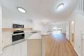 Located in the Mariner Garden community of Stuart, Florida, this two-story home offers three bedrooms, four bathrooms, and a well-designed layout spread across two floors. The main level features a bright, open-concept living and dining area with light hardwood-style flooring and large sliding glass doors that flood the space with natural light and provide views of the outdoors. The kitchen is outfitted with white shaker cabinetry, light countertops, stainless steel Whirlpool appliances including a range, over-the-range microwave, and a double sink, all complemented by tile flooring. A convenient half bath is tucked beneath the staircase on this level. The carpeted staircase leads to the upper floor, where three bedrooms are situated, including a generously sized primary bedroom. The bedrooms feature carpet flooring, ample closet space, and windows that bring in natural light. The bathrooms are finished with tile flooring, white vanities, and tub-shower combinations. An attached garage with an automatic opener provides additional utility and storage. The home is set within a neighborhood lined with palm trees, offering a quintessential South Florida atmosphere. A patio and pantry round out the functional amenities of this comfortable residence.