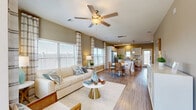 Located in Spring, TX, this two-story home offers a thoughtfully designed layout spread across two floors. The main level opens into a bright, open-concept living, dining, and kitchen area finished with warm wood-look flooring throughout. Large windows flood the living room with natural light, complemented by a ceiling fan overhead. The kitchen is a standout feature, showcasing crisp white cabinetry, a subway tile backsplash, dark quartz countertops, stainless steel appliances, and a central island with pendant lighting — ideal for both cooking and entertaining. A dedicated dining area sits adjacent, creating a seamless flow between spaces.

Upstairs, the primary bedroom is a comfortable retreat with vaulted ceilings, a ceiling fan, natural light from multiple windows, and a walk-in closet. Two additional bedrooms offer similar comfort and style. The home includes four full bathrooms, one of which features a tiled soaking tub and shower combination. A dedicated laundry room with side-by-side washer and dryer adds everyday convenience. Neutral warm-gray wall tones, light hardwood-style floors, and clean white trim give the home a cohesive, modern aesthetic throughout.