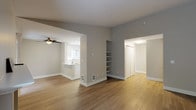 This well-appointed single-floor residence offers a clean, modern aesthetic throughout, highlighted by a neutral color palette, updated flooring, and an open, airy layout. The spacious living area features warm hardwood-style flooring, a tile-surround fireplace, and a large window that fills the room with natural light and views of surrounding greenery. A ceiling fan adds comfort to the adjacent dining area, which flows seamlessly into the kitchen. The kitchen is fully renovated, showcasing crisp white shaker cabinetry, gleaming white quartz countertops, stainless steel appliances including a range and refrigerator, and a peninsula with an undermount sink — ideal for both cooking and casual dining. Built-in open shelving provides additional storage and display space in the main living area. The two bedrooms are carpeted for comfort, each offering natural light through slatted windows and baseboard heating. The bathroom is finished with a white shaker vanity, quartz countertop, large mirror, and a shower-tub combination. A hallway leads to a dedicated walk-in closet area and additional storage, completing this thoughtfully designed and move-in-ready home.