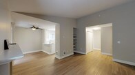 This well-appointed single-floor residence offers a clean, modern aesthetic throughout, highlighted by a neutral color palette, updated flooring, and an open, airy layout. The spacious living area features warm hardwood-style flooring, a tile-surround fireplace, and a large window that fills the room with natural light and views of surrounding greenery. A ceiling fan adds comfort to the adjacent dining area, which flows seamlessly into the kitchen. The kitchen is fully renovated, showcasing crisp white shaker cabinetry, gleaming white quartz countertops, stainless steel appliances including a range and refrigerator, and a peninsula with an undermount sink — ideal for both cooking and casual dining. Built-in open shelving provides additional storage and display space in the main living area. The two bedrooms are carpeted for comfort, each offering natural light through slatted windows and baseboard heating. The bathroom is finished with a white shaker vanity, quartz countertop, large mirror, and a shower-tub combination. A hallway leads to a dedicated walk-in closet area and additional storage, completing this thoughtfully designed and move-in-ready home.