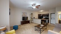 This thoughtfully designed one-bedroom, one-bathroom residence offers a functional and comfortable single-floor layout. The open-concept living and kitchen area serves as the heart of the home, featuring warm neutral tones, plush wall-to-wall carpeting in the living zone, and smooth tile flooring in the kitchen. A ceiling fan with light fixture anchors the living room, which receives natural light through a large window fitted with vertical blinds. The kitchen is well-equipped with dark cabinetry, granite-style countertops, a full suite of black appliances including a refrigerator, electric range, microwave, and dishwasher, along with a double sink and a convenient breakfast bar for casual dining. The bedroom is a serene retreat finished with soft carpeting, a ceiling fan, and a sliding glass door that brings in additional natural light. It connects directly to a generous walk-in closet outfitted with built-in shelving and dual hanging rods, providing ample storage. The bathroom features a full tub and shower combination. The entry foyer transitions seamlessly between tile and carpet, reinforcing the clean, cohesive aesthetic that runs throughout this well-organized and inviting residence.