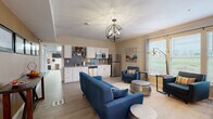 Located at 19766 Pikes Peak Ave in Parker, Colorado, this single-floor community amenity space is thoughtfully designed to provide residents with both social and wellness-oriented areas.

The lounge and common area is open and inviting, featuring light wood-tone flooring, a striking globe chandelier, and large windows that flood the space with natural light and offer views of the surrounding landscape. Comfortable seating arrangements include a bold blue sofa and accent chairs, complemented by metallic side tables and a wall-mounted television. A bistro-height table with bar stools provides an additional spot for casual gathering. A rustic credenza with wine storage and a beverage station adds both function and character to the room.

The kitchenette is seamlessly integrated into the lounge, outfitted with white shaker cabinetry, a gray subway tile backsplash, and a full suite of stainless steel appliances including a refrigerator, dishwasher, and microwave — ideal for hosting community events or casual use.

The fitness center is generously sized and well-equipped, featuring treadmills, an elliptical, a stationary bike, a cable machine, a punching bag, and a weight bench. Floor-to-ceiling mirrors visually expand the space, while a bold geometric-patterned carpet, ceiling fans, and large windows overlooking open fields create an energizing workout environment.