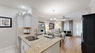 Located in the desirable Post Oak Park neighborhood of Houston, TX, this well-designed one-bedroom, one-bathroom residence offers a thoughtful layout across a single floor. The open-concept living, dining, and kitchen area creates a seamless flow, anchored by warm hardwood flooring and crowned with elegant crown molding throughout. A ceiling fan and chandelier add character to the shared living and dining space, which is bathed in natural light from large windows dressed with floor-length drapes.

The kitchen is equipped with stainless steel appliances, white shaker-style cabinetry, a travertine tile backsplash, granite countertops, and a peninsula with a double undermount sink — ideal for both cooking and casual entertaining. A built-in shelving nook in the living area adds functional display space and architectural interest.

The spacious primary bedroom features plush carpeting, a ceiling fan, and windows that invite natural light, creating a calm and restful retreat. The full bathroom offers a granite-topped vanity with ample cabinetry, tile flooring, and a tub/shower combination. A dedicated closet completes the layout, providing practical storage. This residence combines classic finishes with a warm, cohesive aesthetic throughout.