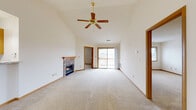 This well-organized 2-bedroom, 2-bathroom residence offers a thoughtfully designed single-floor layout with a welcoming and functional flow throughout. The living room serves as the centerpiece of the home, highlighted by soaring vaulted ceilings, a ceiling fan, a stone-surround gas fireplace, and a sliding glass door that fills the space with natural light while providing outdoor access. Soft carpeting runs throughout the living areas and bedrooms, complementing the warm wood trim and baseboards found across the home. The kitchen is outfitted with rich wood cabinetry, ample counter space, a full suite of white appliances, a built-in microwave, and tile-style flooring that adds durability and easy maintenance. The primary bedroom is generously sized and features a walk-in closet with wire shelving systems for organized storage. Both bathrooms are clean and functional, with the full bath featuring a wide vanity with wood cabinetry, a large mirror, and tile-style flooring. A dedicated laundry area houses a full-size washer and dryer alongside a water heater and wire shelving. Carpeted staircases with wood handrails, two hallways, and thoughtful closet spaces round out this practical and comfortable home.