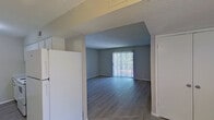 This single-floor residence offers a clean, functional layout designed for comfortable everyday living. The open living and dining area is finished with light hardwood-style flooring and neutral gray walls, creating a bright, cohesive atmosphere. A sliding glass door with vertical blinds fills the living room with natural light and provides outdoor access, while a chandelier overhead adds a warm accent to the adjoining dining space.

The galley-style kitchen is efficiently organized with white cabinetry, light granite-look countertops, and matching white appliances, including an electric range. The layout maximizes storage and counter space along both walls, making it practical for everyday cooking.

The bedrooms are carpeted and finished in soft neutral tones, each featuring windows that bring in natural light. One bedroom offers a connected hallway leading to additional rooms or storage, adding to the overall flow of the unit. Textured ceilings are present throughout the home, consistent with the residential character of the space.

A hallway connects the private areas of the home, with a bathroom accessible along the corridor. The overall color palette — soft grays, warm beiges, and crisp whites — lends the space a clean, move-in-ready feel that is both practical and inviting.
