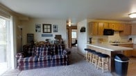 Located at 515-535 W Schindler Pl in Menasha, Wisconsin, this single-floor residence offers a practical and comfortable layout designed for everyday living. The open-concept floor plan seamlessly connects the living area to the kitchen, creating a cohesive and functional shared space.

The living area features wall-to-wall carpeting, providing a warm and cozy atmosphere. Wall décor and personal touches give the space an inviting feel, while a hallway visible from the main area leads to additional rooms, including what appears to be a bedroom with a window allowing natural light into the corridor.

The kitchen is positioned adjacent to the living space and is defined by honey-toned wood cabinetry offering ample storage. A white countertop peninsula serves as a natural divider between the two areas, doubling as a casual dining space with bar-height stools. A built-in microwave and additional counter space make the kitchen both practical and efficient.

Overall, the space presents a straightforward, single-level layout with an open and connected feel between the main living and kitchen zones, making it well-suited for comfortable day-to-day living.