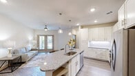 This one-bedroom, one-bathroom unit in Grand Prairie, Texas, offers a thoughtfully designed open-concept layout that maximizes its efficiently proportioned footprint. The kitchen serves as a focal point, featuring a curved granite-topped island with an undermount sink, pendant lighting, white shaker cabinetry with a subway tile backsplash, and a full suite of stainless steel appliances including a gas range, microwave, and French door refrigerator. The island provides casual bar seating, making it ideal for both meal prep and dining.

The living room flows naturally from the kitchen and is finished with wood-look plank flooring, neutral walls, a ceiling fan, and French doors that open to an outdoor patio, allowing natural light to filter through. The bedroom is carpeted for comfort, includes a ceiling fan, a window with outdoor views, and connects to a spacious walk-in closet outfitted with multi-tier shelving and hanging rods. The bathroom features a tiled soaking tub-shower combination, granite vanity countertop, and wood-look tile flooring. A dedicated laundry area accommodates a full-size side-by-side washer and dryer, completing this well-appointed unit.