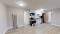 This single-floor, 3-bedroom, 2-bathroom residence offers a thoughtfully designed layout that balances comfort and functionality. The kitchen serves as a central highlight, featuring crisp white shaker-style cabinetry, granite countertops, and a full suite of stainless steel appliances, including a gas range, over-the-range microwave, refrigerator, and dishwasher. A single-basin sink with a modern faucet sits beneath upper cabinets, maximizing storage and workspace efficiency. Light wood-tone flooring runs throughout, lending a clean and contemporary aesthetic that ties the spaces together seamlessly. The neutral color palette on the walls enhances the bright, airy feel of the interior. A wall-mounted HVAC unit provides climate control, ensuring year-round comfort. A doorway visible from the kitchen leads to an adjacent room, reinforcing the open and connected flow of the floor plan. The overall design is practical and move-in ready, with attention to detail evident in the clean trim work, flush-mount lighting, and cohesive material choices throughout. This residence is well-suited for those seeking a modern, low-maintenance living space with ample room across its three bedrooms.