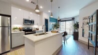 This single-floor residence showcases a thoughtfully designed open-concept layout that seamlessly connects the kitchen, dining, and living areas. The kitchen is a standout feature, equipped with stainless steel appliances including a refrigerator, over-the-range microwave, and electric range. White upper cabinetry pairs with gray lower cabinets and a white quartz island countertop complete with an undermount sink. Pendant lighting with an industrial-style finish illuminates the workspace, while wood-look flooring extends throughout the main living areas.

The living room is anchored by a bold teal accent wall, creating a vibrant backdrop for the space. Large floor-to-ceiling sliding glass doors invite natural light and provide access to an outdoor balcony with exterior views. The bedroom continues the teal accent wall theme and features plush carpeting, a ceiling fan, and windows that allow ample natural light. A dedicated dressing area offers additional storage and flexibility within the room.

The bathroom is finished with large-format white subway tile in the walk-in glass-enclosed shower, wood-look tile flooring, and brushed nickel fixtures, delivering a clean and modern aesthetic throughout.