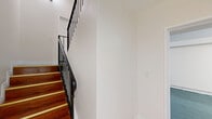 This three-bedroom, two-bathroom multi-level home in Panorama City, Los Angeles, offers a well-organized layout spread across three floors. The ground level provides an attached garage with an automatic opener, painted concrete floors, and ample built-in lighting. The main living floor features a combined kitchen and living area, where warm hardwood flooring flows throughout the open space. The kitchen is equipped with rich cherry wood cabinetry, granite-style countertops, a gas range, over-the-range microwave, and a double-basin sink beneath a window that lets in natural light. The living area benefits from exposed ceiling beams and multiple windows that brighten the space. The upper floor hosts all three bedrooms and two full bathrooms. The bedrooms feature plush carpeting and closets—one with mirrored sliding doors and another with classic bi-fold panels—alongside tall walls that lend an airy feel. The bathrooms are finished with warm wood vanities, granite countertops, and light ceramic tile flooring. Connecting hallways and a staircase tie the floors together efficiently. With neutral tones throughout and a clean, functional design, this home delivers practical comfort in a convenient Los Angeles location.