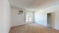 Located at 3545 Mather Field Rd in Rancho Cordova, CA, this single-floor unit offers three bedrooms, two bathrooms, and a practical layout designed to maximize every square foot. The living room features plush carpeting, a textured ceiling, a wall-mounted HVAC unit, and a large window framing pleasant views of surrounding trees, filling the space with natural light. A vertical floor-to-ceiling heating unit is also present, adding a functional architectural element to the room. The galley-style kitchen is efficiently laid out with white cabinetry, light countertops, a stainless sink, and wood-look vinyl flooring, providing ample storage and workspace. The dining area flows naturally from the kitchen, supporting everyday living. Each of the three carpeted bedrooms includes windows overlooking greenery, and the spacious primary bedroom is complemented by a generously sized walk-in closet with built-in hanging rods. Two additional closets serve the secondary bedrooms. The bathrooms feature wood-look vinyl flooring, light countertops with under-sink cabinetry, large mirrors, and clean white finishes throughout. Neutral tones, textured ceilings, and consistent flooring materials create a cohesive and functional living environment throughout the home.