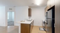 Located at 3534 E Capitol St NE in Washington, DC, this 2-bedroom, 2-bathroom unit offers a thoughtfully designed single-floor layout. The open-concept living, dining, and kitchen area serves as the heart of the home, featuring light wood-style flooring that creates a clean, modern aesthetic. The kitchen is well-appointed with warm wood-tone cabinetry, ample upper and lower storage, a peninsula with a built-in sink and white countertops, and black appliances including a refrigerator, range, and microwave. Natural light fills the space from multiple windows fitted with horizontal blinds. Both bedrooms are carpeted for comfort and include large windows that bring in generous daylight. Three closets provide ample storage throughout the unit. The two bathrooms are finished with large-format gray tile flooring and warm wood vanities; one bathroom features a full tub-shower combination, while the other offers a walk-in style closet with wire shelving. A dedicated laundry area adds everyday convenience, and a connecting hallway ties the layout together efficiently. The overall design presents a contemporary and functional living space suited for a range of lifestyles.