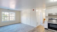 This single-floor unit offers a clean, functional layout designed for comfortable everyday living. The open-concept living area features neutral-toned walls, plush wall-to-wall carpeting, and smooth white ceilings, creating a bright and welcoming atmosphere. A large window allows natural light to fill the space, enhancing its airy feel.

The kitchen flows seamlessly from the living area and is finished with wood-look flooring, crisp white cabinetry, light countertops, and a full suite of stainless steel appliances, including a range, dishwasher, and refrigerator. A range hood and under-cabinet space add to the kitchen's practicality.

The bedrooms are generously sized, each featuring soft carpeting and multiple windows that invite an abundance of natural light and outdoor views of the surrounding neighborhood. The rooms offer a calm, neutral palette well-suited to a variety of furnishing styles.

A dedicated laundry area houses a stacked washer and dryer unit, providing the convenience of in-unit laundry. The bathroom is clean and straightforward, featuring a full tub and shower combination with chrome fixtures and wood-look flooring. Throughout the unit, consistent finishes and thoughtful details contribute to a cohesive and move-in-ready living environment.