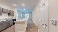 This single-floor, 2-bedroom, 1-bathroom residence offers a thoughtfully designed layout that maximizes comfort and functionality. The open-concept kitchen and living area form the heart of the home, anchored by a generously sized kitchen island with granite-look countertops that provides both prep space and a natural gathering point. The kitchen is outfitted with rich, gray-toned shaker-style cabinetry, black appliances including a range, built-in microwave, refrigerator, and dishwasher, all set atop durable wood-look flooring that extends throughout the main living areas. The living room receives natural light through multiple windows fitted with horizontal blinds and features a ceiling fan for added comfort.

Both bedrooms are carpeted and offer a warm, quiet retreat. The primary bedroom stands out with multiple windows on adjacent walls, flooding the room with natural light, and includes a dedicated walk-in closet with wire shelving systems for organized storage. The second bedroom also features a window with outdoor views and access to an additional closet. The full bathroom is finished consistently with the kitchen, featuring a granite-look vanity countertop, taupe cabinetry, a tub-shower combination, and brushed nickel fixtures. Clean neutral walls and consistent finishes throughout give the space a cohesive, move-in-ready feel.