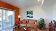 Located at 4333 Parkway Village Dr in Grove City, Ohio, this single-floor residence offers a comfortable and well-designed living environment. The living area is a standout feature, showcasing soaring vaulted ceilings that lend a sense of openness and airiness to the space. A bold orange accent wall adds a warm, vibrant contrast to the crisp white walls and ceiling, creating an inviting and energetic atmosphere. Natural light filters in through a sliding glass door fitted with vertical blinds, providing both brightness and easy access to the outdoors. The room is finished with plush carpeting underfoot, contributing to a cozy feel throughout. The layout is practical and functional, with ample room for comfortable seating and everyday living. The overall ambiance of the space balances modern simplicity with warm, welcoming design touches, making it a charming home in the Grove City community.