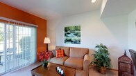 Located at 4333 Parkway Village Dr in Grove City, Ohio, this single-floor residence offers a comfortable and well-designed living environment. The living area is a standout feature, showcasing soaring vaulted ceilings that lend a sense of openness and airiness to the space. A bold orange accent wall adds a warm, vibrant contrast to the crisp white walls and ceiling, creating an inviting and energetic atmosphere. Natural light filters in through a sliding glass door fitted with vertical blinds, providing both brightness and easy access to the outdoors. The room is finished with plush carpeting underfoot, contributing to a cozy feel throughout. The layout is practical and functional, with ample room for comfortable seating and everyday living. The overall ambiance of the space balances modern simplicity with warm, welcoming design touches, making it a charming home in the Grove City community.