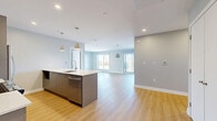 Located at 17 Place de la Triade in Pointe-Claire, Quebec, this well-appointed 3-bedroom, 2-bathroom unit offers a thoughtfully designed open-concept layout finished with modern touches throughout. Light hardwood flooring flows seamlessly across the main living areas, enhancing the bright and airy atmosphere created by large windows and sliding glass doors.

The kitchen is a standout feature, equipped with stainless steel appliances including a range and French door refrigerator, two-tone cabinetry combining light wood uppers with grey lower cabinets, a subway tile backsplash, and a generous island with a white quartz countertop and undermount sink — ideal for both cooking and entertaining. Pendant lighting above the island adds a polished finishing touch. The kitchen opens directly into the combined dining and living area, which benefits from natural light and access to a private balcony with outdoor views.

The three bedrooms are comfortably sized, each featuring large windows that invite ample natural light. The primary bedroom is particularly well-lit with dual windows and a wall-mounted A/C unit.

Both bathrooms are finished with warm wood cabinetry and large-format tile flooring. One features a glass-enclosed shower, while the other offers a shower-tub combination. Additional conveniences include a dedicated laundry room, four closets, and a hallway entrance.