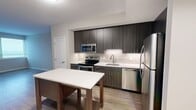 Located at 2827 Telek Place in Alexandria, Virginia, this thoughtfully designed two-bedroom, two-bathroom residence offers a comfortable and modern living experience across a single floor. The contemporary kitchen serves as a functional centerpiece, featuring dark wood-grain cabinetry, light quartz countertops, a subway tile backsplash, and a full suite of stainless steel appliances including a range, microwave, dishwasher, and refrigerator. A kitchen island provides additional prep and dining space, while an adjacent pantry closet adds convenient storage. The open layout flows naturally into the living area, finished with durable wood-style flooring that adds warmth and cohesion. Both bedrooms are generously proportioned, with the primary bedroom offering notable square footage, carpet flooring, and a bright window framing natural light. The second bedroom mirrors this comfortable feel with its own window and soft carpeting. Each of the two bathrooms is finished in a clean, neutral palette with large-format tile, a tub-shower combination, and modern vanity cabinetry. Two dedicated closets throughout the home provide practical storage solutions. The overall design reflects a clean, contemporary aesthetic with neutral tones, creating a calm and move-in-ready environment.