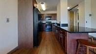 Located on Oakland Street in Morgantown, WV, this efficient 540-square-foot, one-bedroom, one-bathroom apartment is designed to maximize every inch of its single-floor layout. The kitchen is a standout feature, boasting rich dark-wood cabinetry, black granite countertops, hardwood flooring, and a full suite of black appliances including an electric range, built-in microwave, dishwasher, and refrigerator. A peninsula counter extends the workspace and adds a natural division between the kitchen and living area. The open living space continues the hardwood flooring and benefits from windows that invite natural light. The bedroom spans 170 square feet and is finished with wall-to-wall carpet, neutral walls, and large windows offering outdoor views of the surrounding Morgantown area. A full-length mirrored sliding closet door adds both functionality and a sense of added space. The bathroom features light tile flooring, a white tub-shower combination with a curved curtain rod, a dark wood vanity with storage, and a well-lit mirror. This apartment offers a practical and comfortable layout well-suited for a single occupant or student in the Morgantown area.