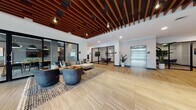 Located at 1631 Paterson Plank Rd in Secaucus, NJ, this thoughtfully designed amenity floor offers a rich variety of social and recreational spaces united by a cohesive modern aesthetic. The welcoming lobby greets visitors with striking rich wood slat ceiling details, large-format light wood-look tile flooring, and a comfortable seating arrangement anchored by a patterned area rug. A glass-enclosed conference room and a sleek elevator are also accessible from the lobby. The spacious lounge area features herringbone-patterned hardwood floors, floor-to-ceiling sheer drapery, and abundant natural light. Vibrant accent chairs in bold orange and yellow tones add personality, while a living moss wall installation creates a distinctive biophilic focal point. A communal gathering space offers long wooden dining tables with bench seating, centered around a dramatic dark feature wall with pendant lighting and a mounted flat-screen TV. The game room is a standout, showcasing a blue felt pool table beneath Edison bulb pendant lights, a large wall-mounted TV, and neon "GAME" signage that sets a lively tone. Throughout the floor, light wood flooring, recessed lighting, and textured wall treatments create a warm yet contemporary ambiance suited for both relaxation and socializing.