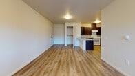 Located at 507 East Cope Industrial Way in Palmer, Alaska, Unit 220 is a thoughtfully designed single-floor residence that offers a clean, modern aesthetic throughout. The open living area greets you upon entry, featuring warm wood-look luxury vinyl plank flooring, crisp white walls, and a front door flanked by windows that invite natural light into the space. A dedicated laundry area with an in-unit washer is conveniently tucked nearby.

The kitchen is a functional highlight, outfitted with rich dark cabinetry, granite-style countertops, a breakfast bar peninsula, and white appliances including an electric range and refrigerator. The layout flows seamlessly from the kitchen into the main living space, making it well-suited for everyday living.

The bedrooms are carpeted for comfort and feature multiple windows that provide views of the surrounding neighborhood and ample natural light, creating bright and welcoming retreats.

The bathroom is notably designed with accessibility in mind, featuring a roll-in shower with grab bars, a fold-down bench seat, a handheld showerhead, and wood-look flooring, paired with a vanity with granite-style countertops. This unit combines practical functionality with a clean, contemporary finish throughout.