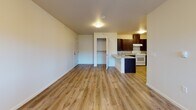 Located at 507 East Cope Industrial Way in Palmer, Alaska, Unit 220 is a thoughtfully designed single-floor residence that offers a clean, modern aesthetic throughout. The open living area greets you upon entry, featuring warm wood-look luxury vinyl plank flooring, crisp white walls, and a front door flanked by windows that invite natural light into the space. A dedicated laundry area with an in-unit washer is conveniently tucked nearby.

The kitchen is a functional highlight, outfitted with rich dark cabinetry, granite-style countertops, a breakfast bar peninsula, and white appliances including an electric range and refrigerator. The layout flows seamlessly from the kitchen into the main living space, making it well-suited for everyday living.

The bedrooms are carpeted for comfort and feature multiple windows that provide views of the surrounding neighborhood and ample natural light, creating bright and welcoming retreats.

The bathroom is notably designed with accessibility in mind, featuring a roll-in shower with grab bars, a fold-down bench seat, a handheld showerhead, and wood-look flooring, paired with a vanity with granite-style countertops. This unit combines practical functionality with a clean, contemporary finish throughout.