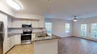 This single-story residence is designed with an open-concept layout that seamlessly connects the kitchen and living areas. The kitchen is a functional centerpiece, showcasing granite countertops, white shaker-style cabinetry, a classic subway tile backsplash, and a full suite of stainless steel appliances, including a refrigerator, range, over-the-range microwave, and dishwasher. A peninsula with a built-in sink provides additional prep space and serves as a natural divider between the kitchen and the open living area.

The living space is bright and welcoming, with wood-look flooring underfoot and multiple windows fitted with blinds that invite natural light while maintaining privacy. A ceiling fan adds to the comfort of the area.

The bedroom is carpeted for warmth and comfort, featuring its own ceiling fan and a generously sized window with outdoor views. The full bathroom includes a granite-topped vanity, wood-look flooring, and a tub-shower combination with clean white tile surround. A separate water closet provides additional convenience. Completing the layout is a dedicated in-unit laundry area equipped with a full-size washer and dryer and an overhead storage shelf.