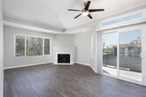 Located at 2111 W 17th St in Santa Ana, California, this single-floor unit offers a thoughtfully updated interior with a cohesive modern aesthetic. The open-concept living area is a standout feature, highlighted by a ceiling fan, vaulted ceiling detail, a wood-burning fireplace, and a large window that allows natural light to fill the space. Sliding glass doors provide access to an outdoor area, enhancing the sense of openness. Wood-style flooring runs throughout the unit, adding warmth and continuity across rooms. The kitchen is well-appointed with two-tone cabinetry — dark gray lower cabinets paired with glossy white upper cabinets — complemented by light quartz countertops, stainless steel appliances including a range, microwave, and dishwasher, and a pass-through that connects to the living area. The bedrooms feature neutral gray walls, wood-style flooring, and mirrored sliding closet doors that reflect light and add depth. The bathrooms are finished with wood-look flooring, a bathtub and shower combination, updated vanities, and practical overhead lighting. Cabinet storage above the toilet in one bathroom adds functional convenience. The overall palette of soft grays and whites, combined with consistent flooring and clean-lined finishes, gives the entire space a fresh and move-in-ready character.