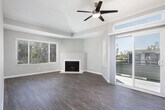 Located at 2111 W 17th St in Santa Ana, California, this single-floor unit offers a thoughtfully updated interior with a cohesive modern aesthetic. The open-concept living area is a standout feature, highlighted by a ceiling fan, vaulted ceiling detail, a wood-burning fireplace, and a large window that allows natural light to fill the space. Sliding glass doors provide access to an outdoor area, enhancing the sense of openness. Wood-style flooring runs throughout the unit, adding warmth and continuity across rooms. The kitchen is well-appointed with two-tone cabinetry — dark gray lower cabinets paired with glossy white upper cabinets — complemented by light quartz countertops, stainless steel appliances including a range, microwave, and dishwasher, and a pass-through that connects to the living area. The bedrooms feature neutral gray walls, wood-style flooring, and mirrored sliding closet doors that reflect light and add depth. The bathrooms are finished with wood-look flooring, a bathtub and shower combination, updated vanities, and practical overhead lighting. Cabinet storage above the toilet in one bathroom adds functional convenience. The overall palette of soft grays and whites, combined with consistent flooring and clean-lined finishes, gives the entire space a fresh and move-in-ready character.
