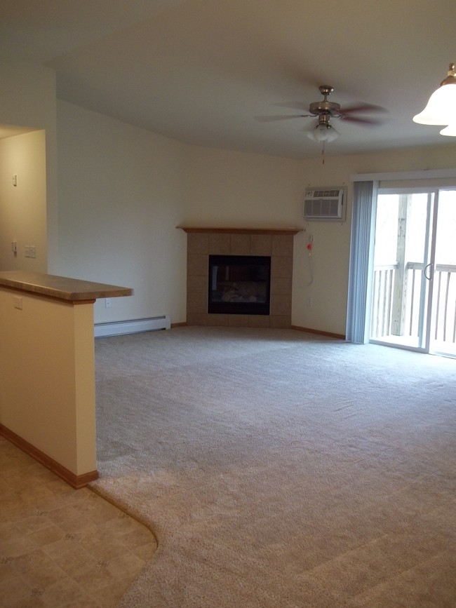 Spacious living room with warm inviting gas fireplace. - Park Creek Apartments