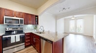 This single-story residence showcases a thoughtfully designed open-concept layout that connects the main living areas through a series of elegant arched doorways. The kitchen is a functional centerpiece, equipped with rich dark mahogany cabinetry, granite countertops, a full suite of stainless steel appliances—including a refrigerator, electric range, built-in microwave, and dishwasher—and a peninsula that opens toward the living area. A glass tile backsplash and track lighting add refined detail to the space.

The living area features warm wood-style flooring, crown molding, and a ceiling fan, with natural light entering through French doors that lead to an outdoor view. A separate dining or flex space connects seamlessly via another arched opening, maintaining the home's cohesive flow.

The bedrooms are carpeted for comfort, each benefiting from ceiling fans and windows with outdoor views. The primary bathroom includes a granite-topped vanity with dark cabinetry, wood-style flooring, a large mirror with overhead lighting, a walk-in closet, and a separate water closet. A secondary bathroom mirrors the same finishes, maintaining consistency throughout the residence.