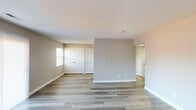 This single-floor residence offers a clean, neutral aesthetic with consistent light-toned laminate wood flooring running throughout the living areas and bedrooms. The open living area is bright and airy, featuring vertical blinds on a sliding glass door that fills the space with natural light and provides access to the outdoors. Textured ceilings add a classic touch, while crisp white baseboards and neutral warm-gray walls create a welcoming atmosphere.

The galley-style kitchen is well-equipped, featuring warm honey-toned wood cabinetry, dark granite countertops, a double-basin sink, and white appliances including a range and dishwasher. Recessed lighting overhead provides ample illumination, and a louvered bifold door adds functional detail.

Multiple bedrooms are present throughout the space, each offering laminate flooring, natural light from windows with blinds, and generous closet storage — including double-door closets and a standard closet with an exposed rod. The rooms provide versatile, open layouts suitable for a variety of furniture arrangements.

The bathroom is neatly appointed with a warm wood-toned vanity, light countertop, a wall-mounted mirror with overhead lighting, and a clean white tub-shower combination with chrome fixtures. Overall, the space presents a tidy, move-in-ready environment with practical finishes and a cohesive design throughout.