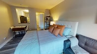 Located at 5101 N Sheridan Road in Chicago's vibrant Edgewater neighborhood, this single-floor studio offers a smart, open-concept layout that maximizes every inch of the space. The main living area serves as a combined sleeping and lounge space, featuring warm wood-look flooring, neutral gray walls, and a cozy ambiance accentuated by soft lighting. A tufted upholstered headboard anchors the sleeping area, complemented by a sectional sofa and open shelving unit that add both function and style.

The kitchen is thoughtfully designed with crisp white shaker cabinetry, dark countertops, and a classic subway tile backsplash. Stainless steel appliances — including a full-size refrigerator, gas range, microwave, and dishwasher — make the space fully equipped for everyday living. A secondary kitchen area with additional appliances and a utility cart provides extra prep and storage flexibility.

The bathroom is clean and modern, featuring a white vanity with a dark countertop, a large mirror with overhead lighting, and a tiled shower. Consistent wood-look flooring runs throughout the unit, tying each area together seamlessly. A baseboard heating system ensures comfort year-round. This well-appointed studio combines practicality with contemporary style in one of Chicago's most accessible lakeside neighborhoods.